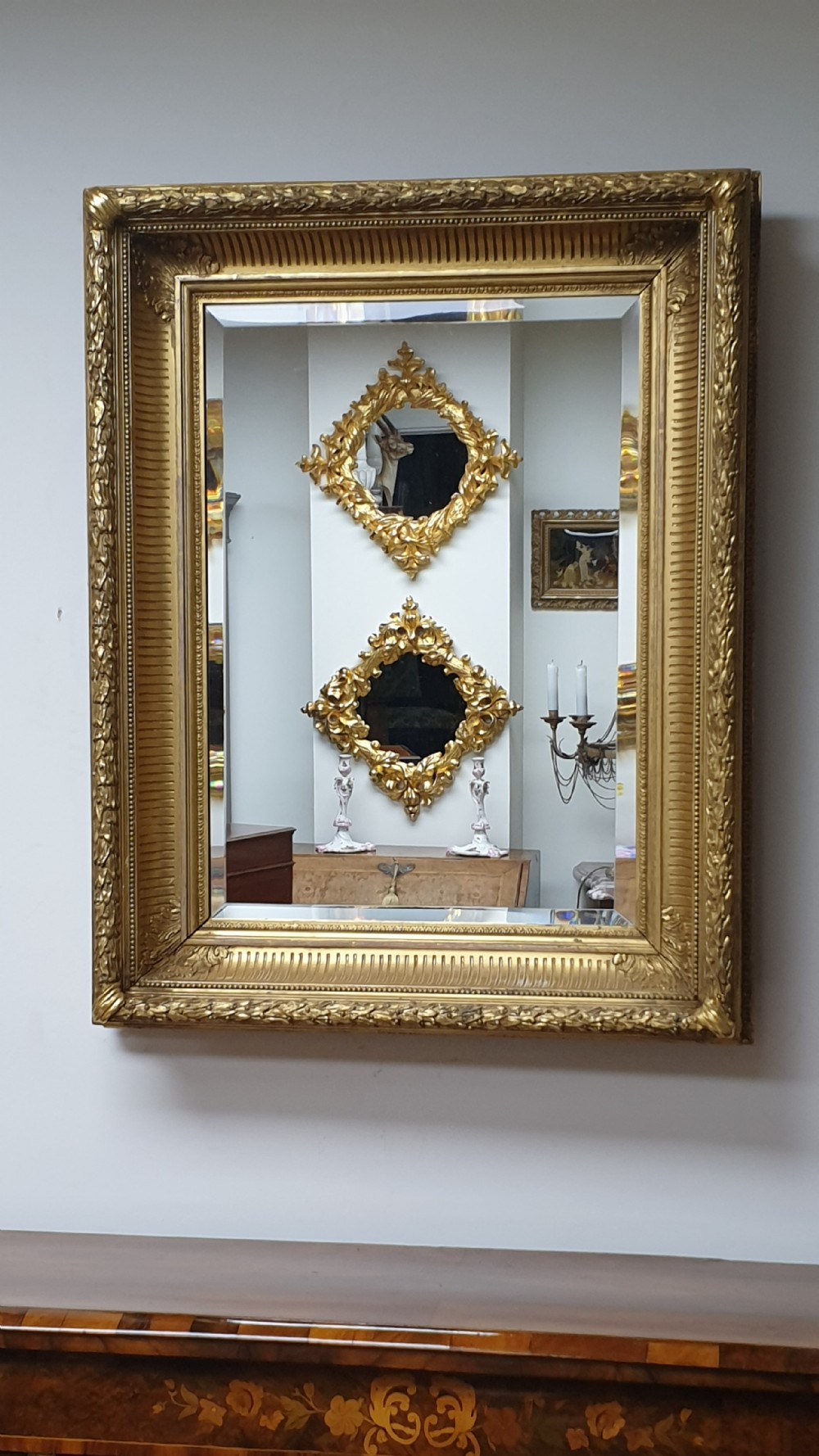 A rectangular antique wall mirror featuring a detailed gold giltwood frame with fluted moulding, leaf trim, and bevelled glass. View II