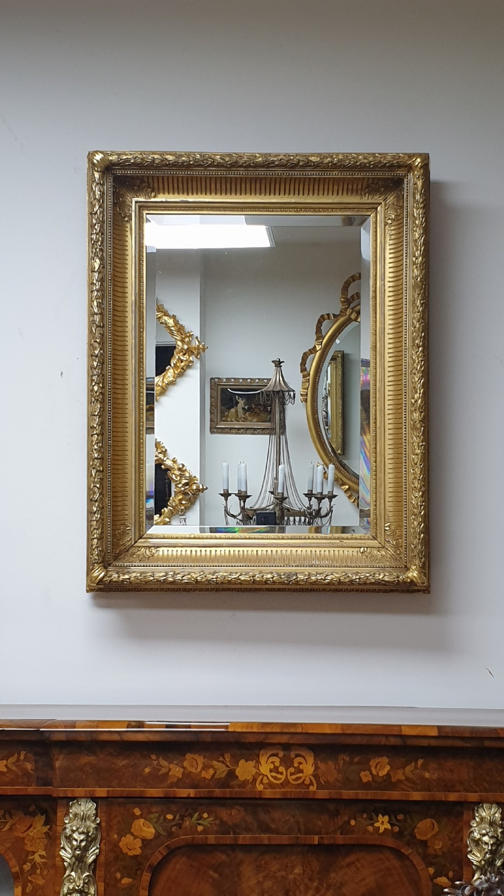 A rectangular antique wall mirror featuring a detailed gold giltwood frame with fluted moulding, leaf trim, and bevelled glass. View III