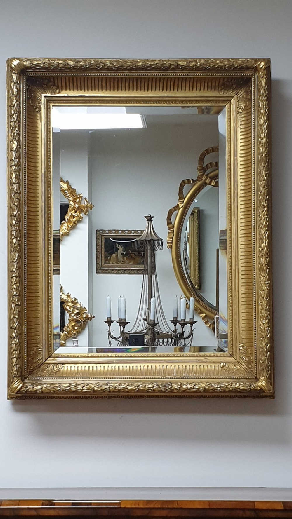 A rectangular antique wall mirror featuring a detailed gold giltwood frame with fluted moulding, leaf trim, and bevelled glass. View IV