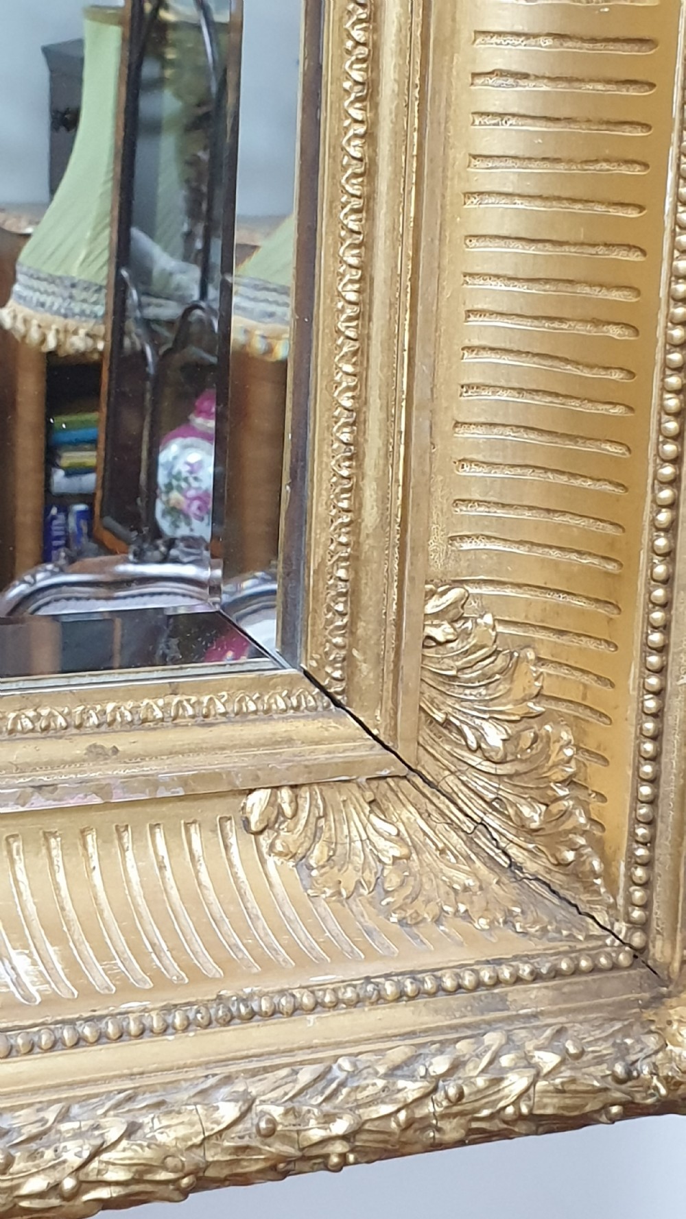 A rectangular antique wall mirror featuring a detailed gold giltwood frame with fluted moulding, leaf trim, and bevelled glass. View VI