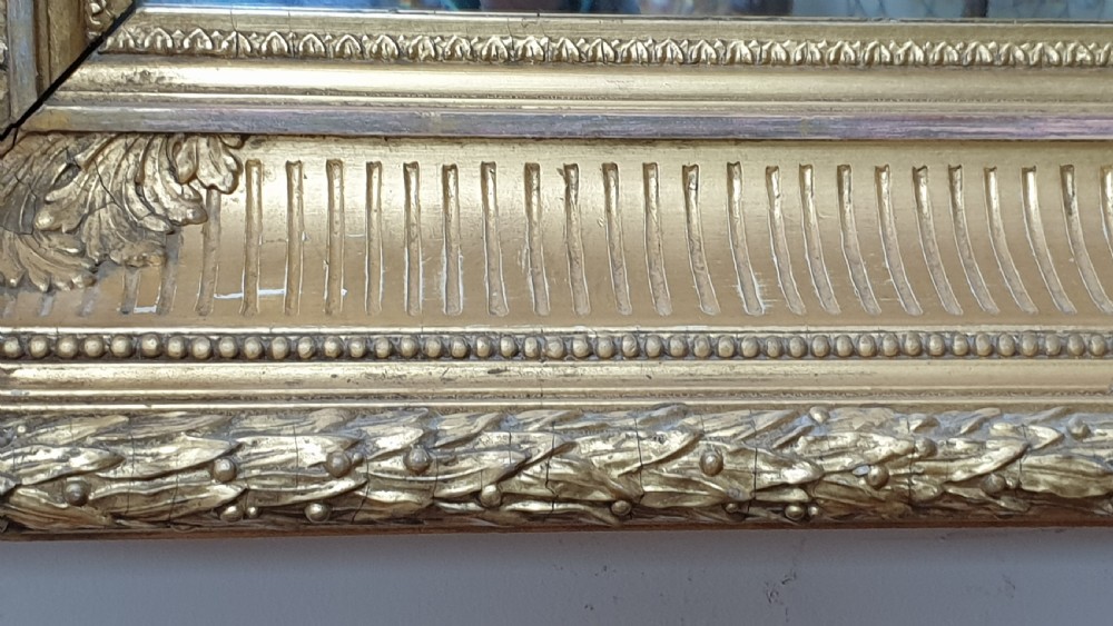 A rectangular antique wall mirror featuring a detailed gold giltwood frame with fluted moulding, leaf trim, and bevelled glass. View VII