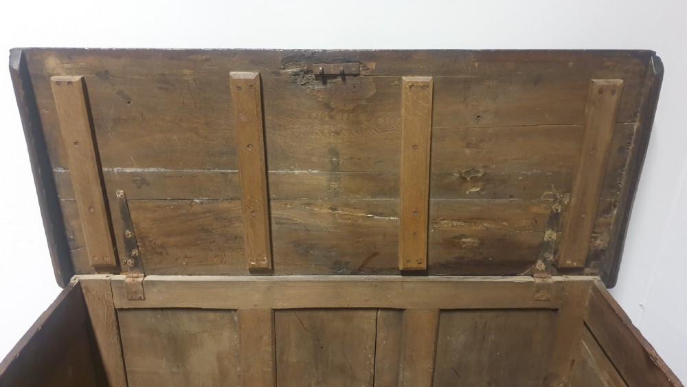 A dark brown carved oak coffer featuring three geometrically moulded front panels, split baluster decoration, and turned bun feet. View VII