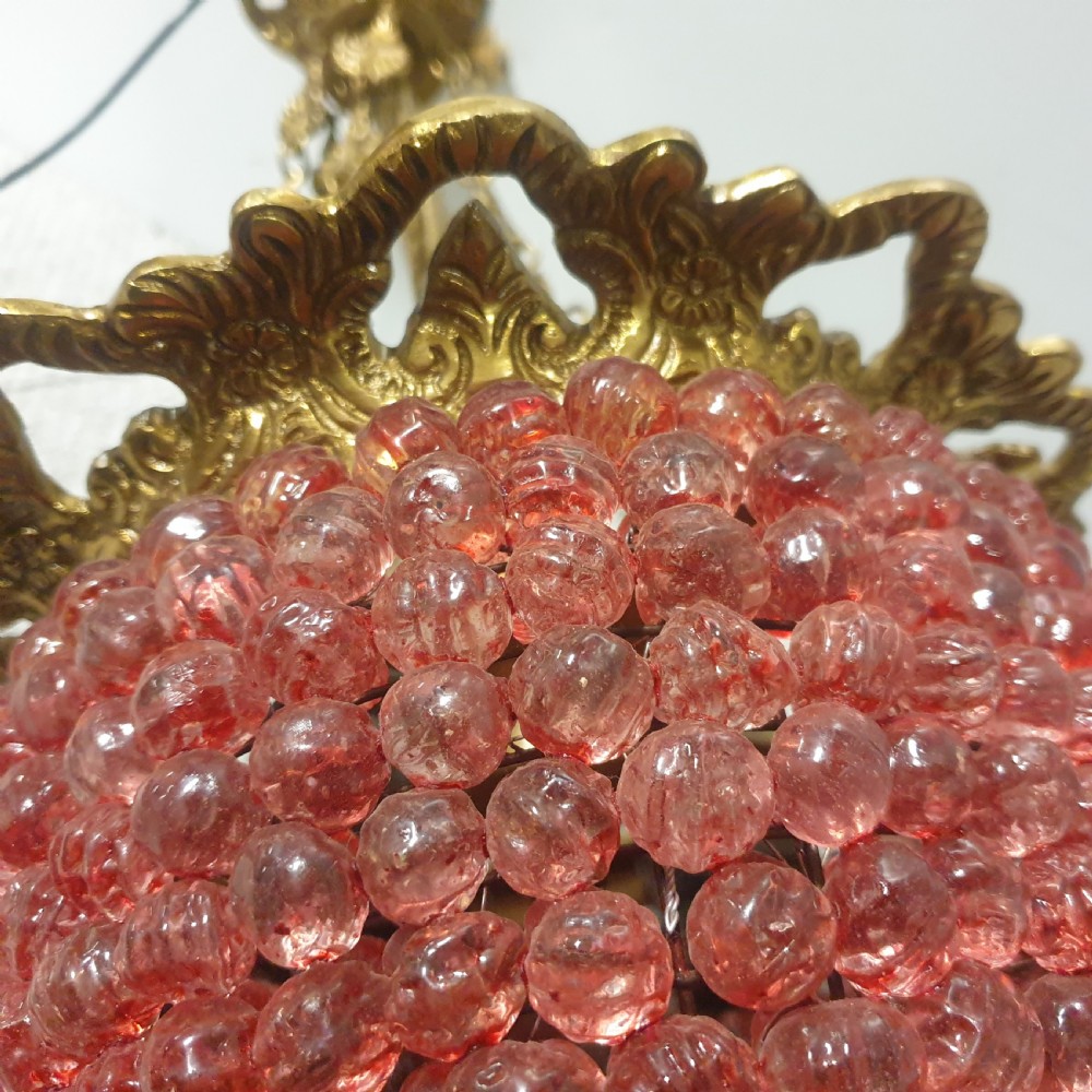 A gilt brass pendant chandelier featuring decorative leaf-motif chains and a teardrop-shaped shade formed of densely woven pink glass beads. View IV
