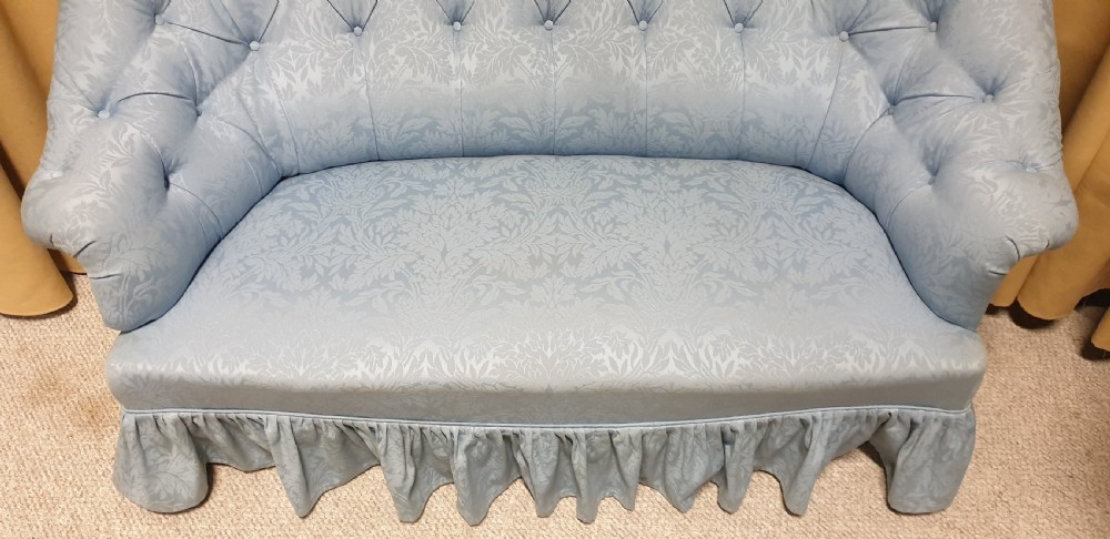 A light blue damask upholstered two-seater settee featuring deep buttoning across the backrest and a pleated base skirt. View V