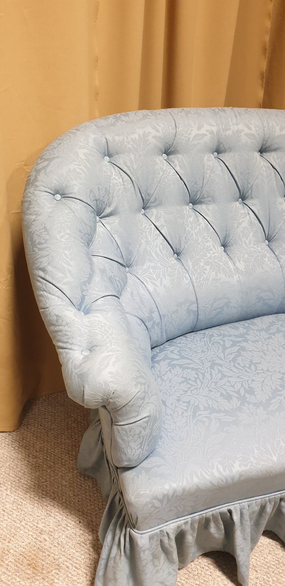 A light blue damask upholstered two-seater settee featuring deep buttoning across the backrest and a pleated base skirt. View VII