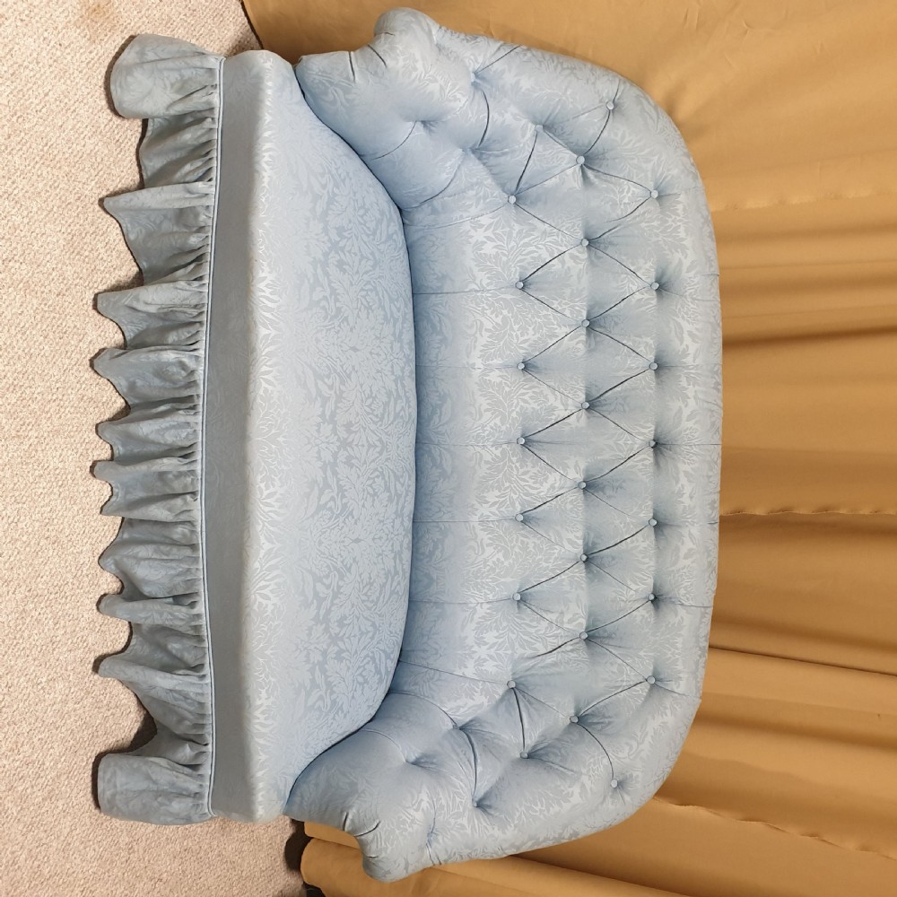 A light blue damask upholstered two-seater settee featuring deep buttoning across the backrest and a pleated base skirt. View IX