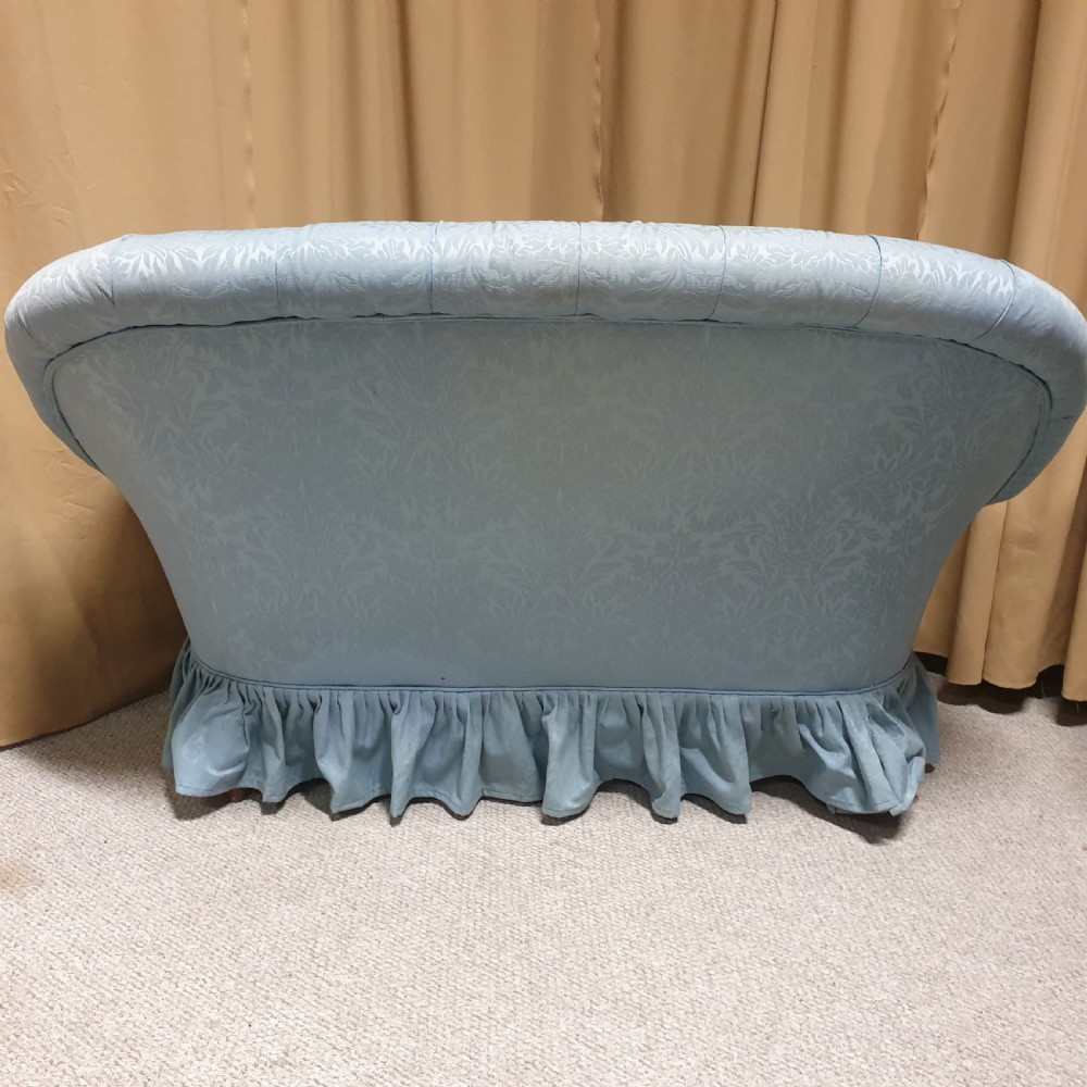 A light blue damask upholstered two-seater settee featuring deep buttoning across the backrest and a pleated base skirt. View X