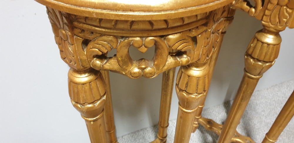 A pair of tall French giltwood torchere stands featuring circular inset marble tops, carved floral aprons, fluted legs, and cross-stretchers with central finials. View III