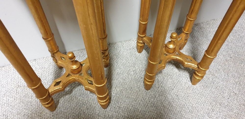 A pair of tall French giltwood torchere stands featuring circular inset marble tops, carved floral aprons, fluted legs, and cross-stretchers with central finials. View V