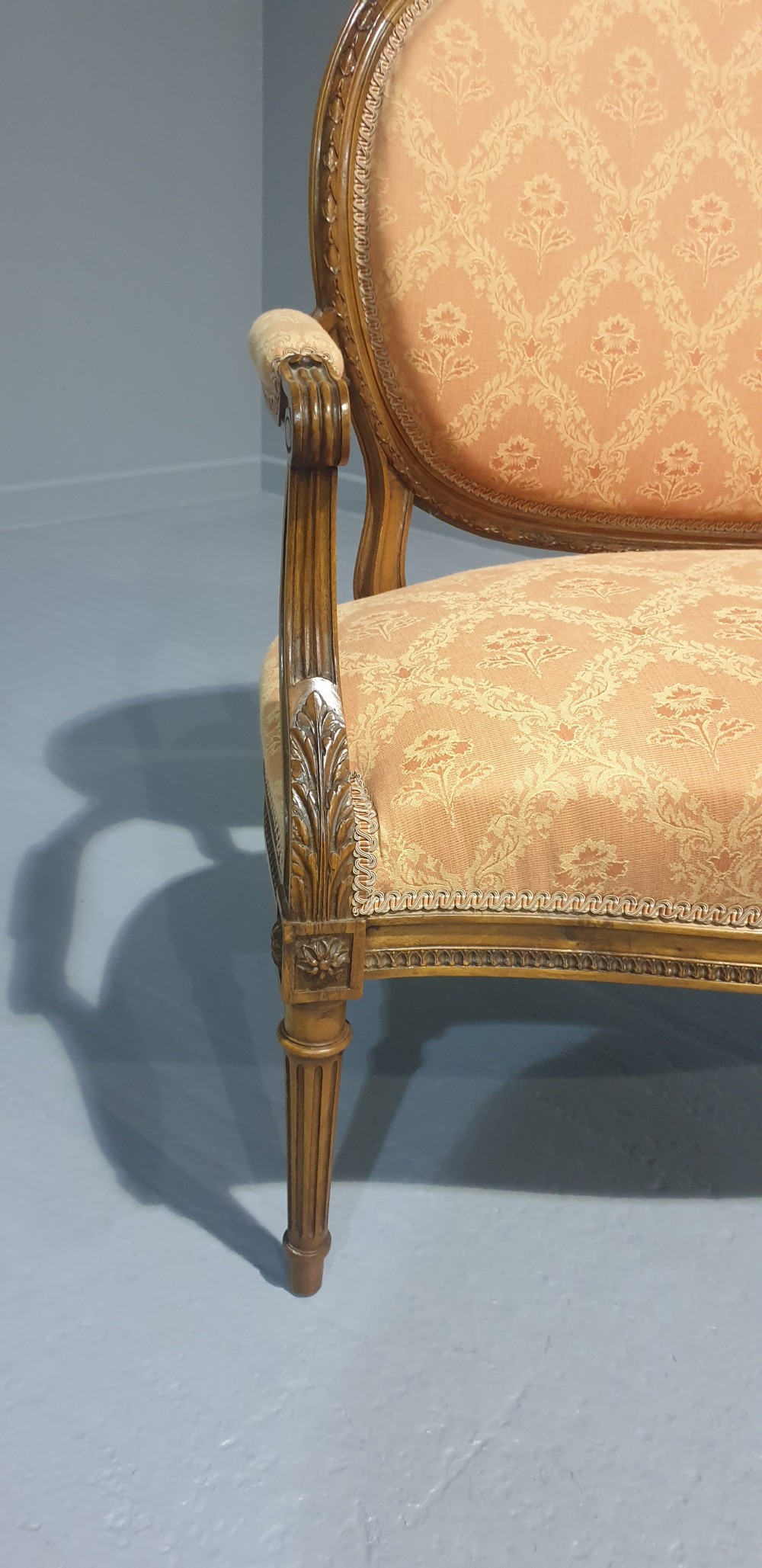A Louis XVI style French walnut two-seat sofa featuring an oval upholstered backrest, carved timber frame, and turned fluted legs. View III
