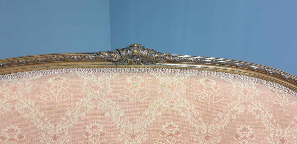 A Louis XVI style French walnut two-seat sofa featuring an oval upholstered backrest, carved timber frame, and turned fluted legs. View VI