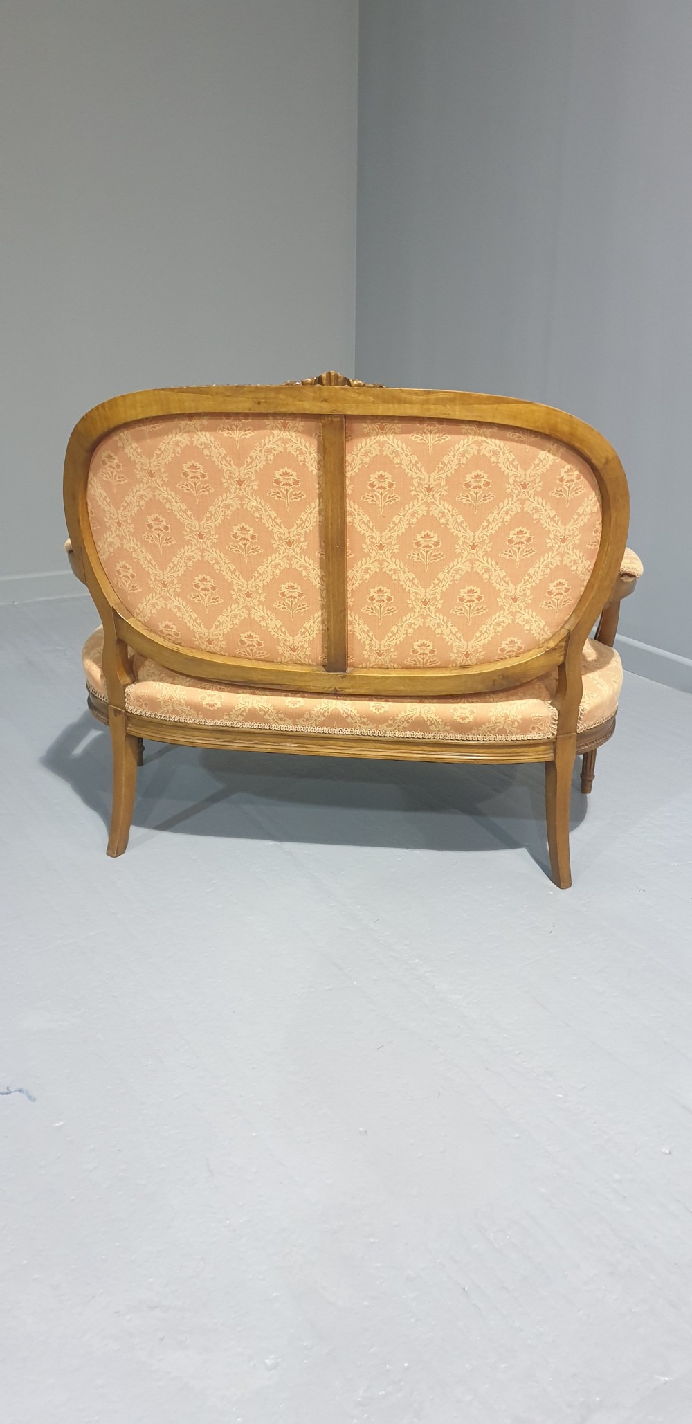 A Louis XVI style French walnut two-seat sofa featuring an oval upholstered backrest, carved timber frame, and turned fluted legs. View VIII