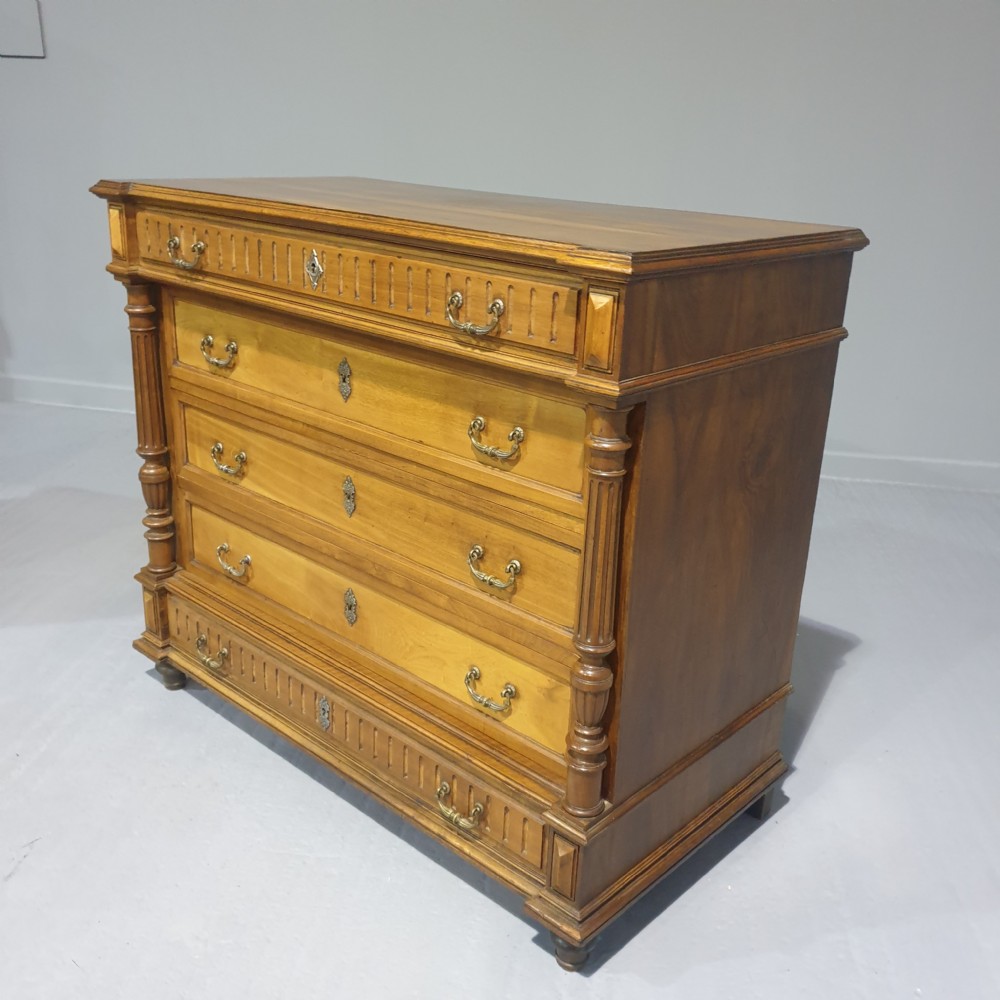 A French walnut chest of drawers featuring five drawers with brass handles, fluted carved top and bottom panels, and turned side columns. View VII