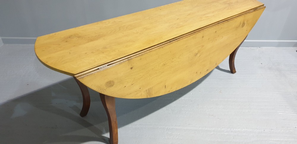 A large French farmhouse dining table featuring a light pine oval top supported by dark fruitwood cabriole legs. View VIII