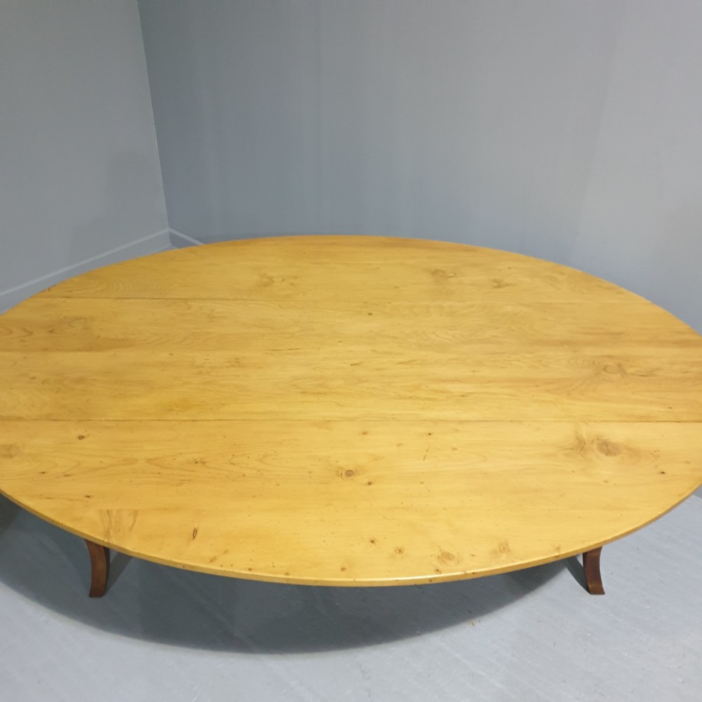 A large French farmhouse dining table featuring a light pine oval top supported by dark fruitwood cabriole legs. View III