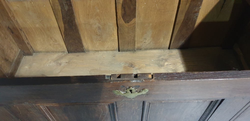 A 17th-century dark oak mule chest featuring four recessed front panels, a bottom drawer with brass knobs, central brass escutcheons, and turned bun feet. View IX