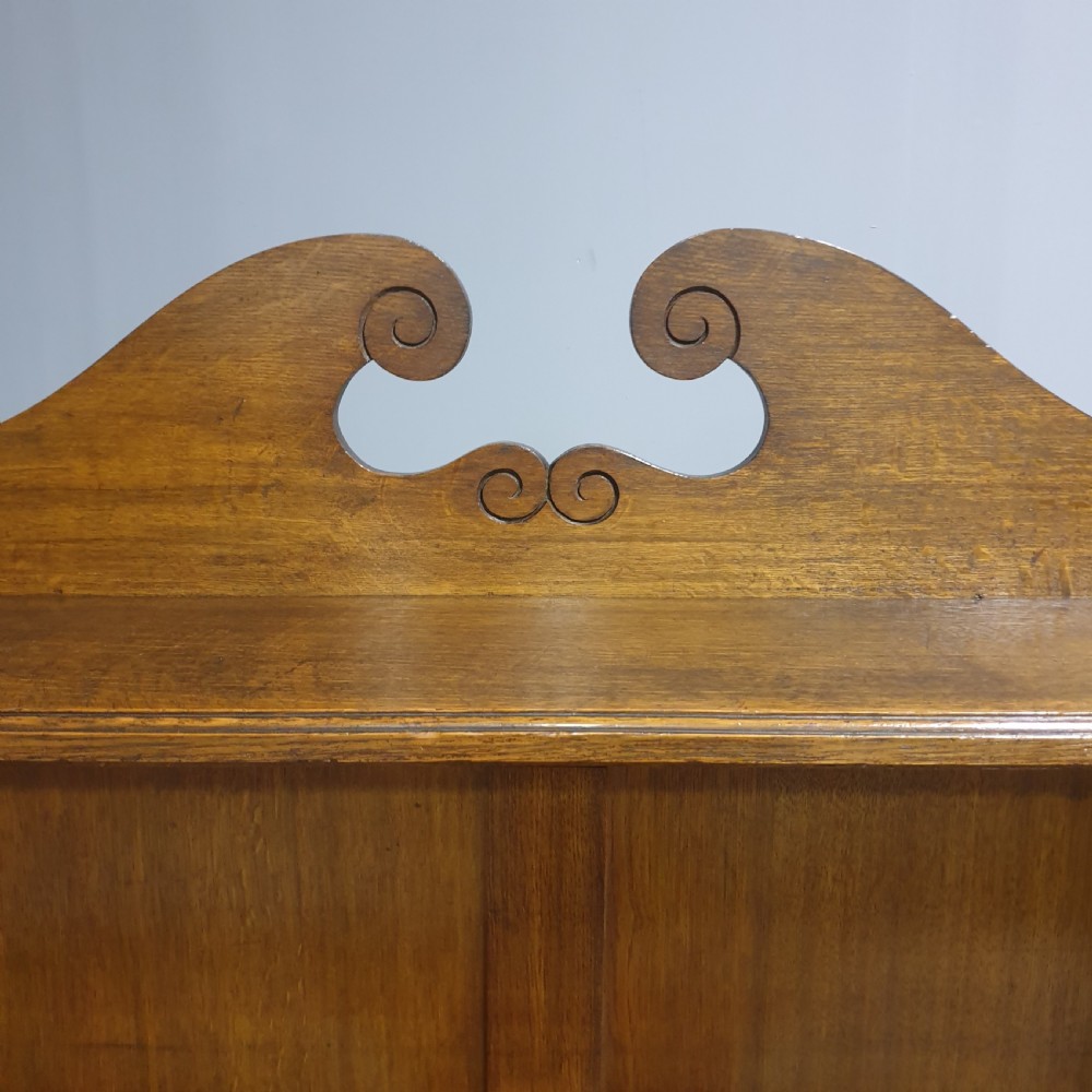 A Victorian medium brown oak open bookcase featuring a carved scroll pediment, adjustable shelves, and two drawers at the base with brass handles. View VIII