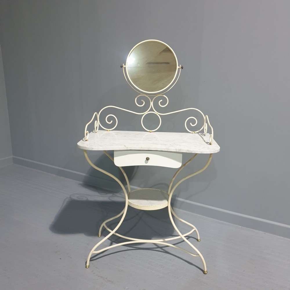 A cream-painted iron dressing table featuring a marble top, a central drawer, a lower shelf, and an attached swivelling circular mirror.
