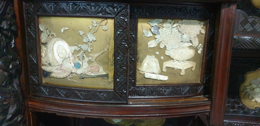 An intricately carved dark wood Japanese Meiji period Shibayama cabinet featuring multi-tiered asymmetrical shelves and gold lacquer panels inset with shell and bone motifs. View XIV