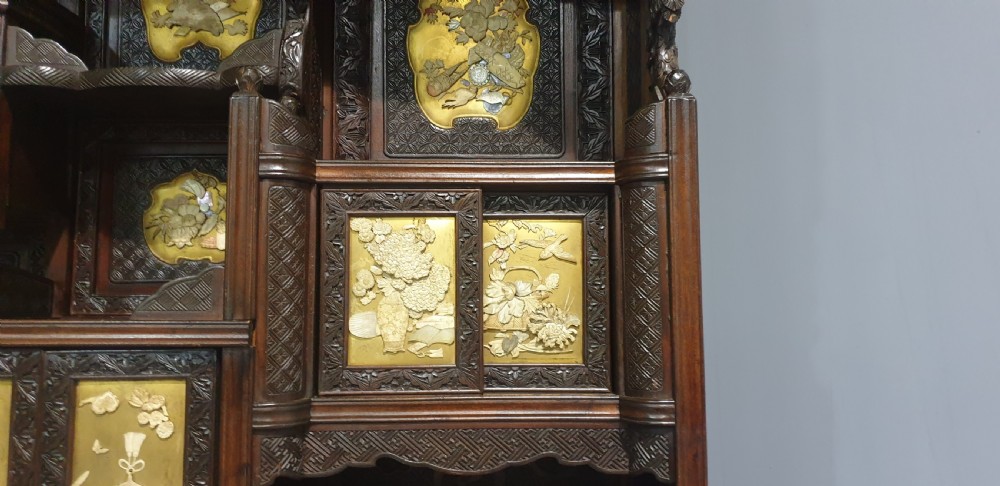 An intricately carved dark wood Japanese Meiji period Shibayama cabinet featuring multi-tiered asymmetrical shelves and gold lacquer panels inset with shell and bone motifs. View XIX