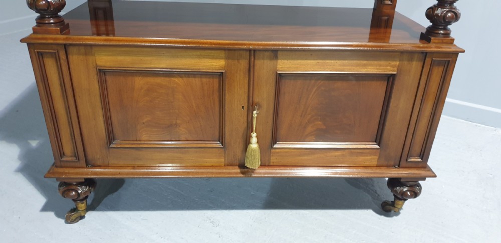 A Victorian mahogany buffet server featuring a carved scroll splashback, turned columns, a two-door lower cupboard, and brass castors. View VII