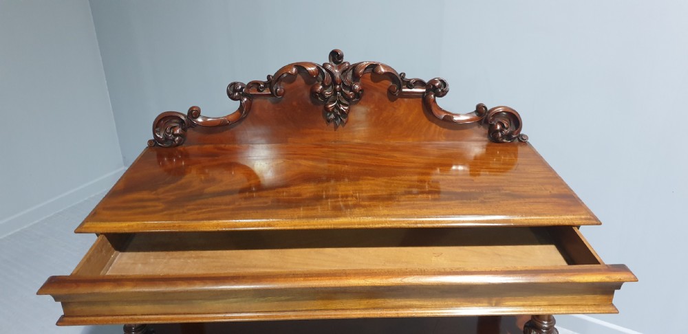 A Victorian mahogany buffet server featuring a carved scroll splashback, turned columns, a two-door lower cupboard, and brass castors. View IX