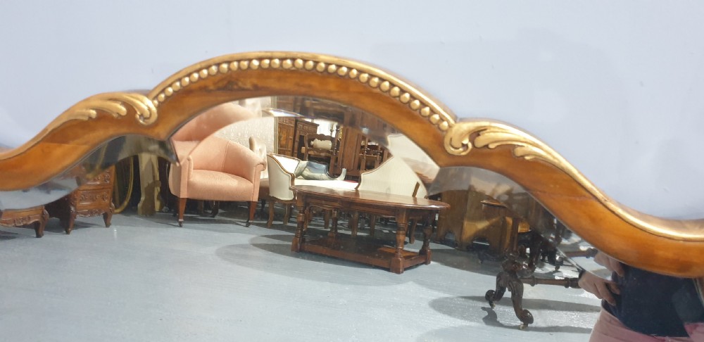 A shaped walnut overmantel mirror featuring gilded beaded borders and leaf accents framing a large central plate. View IV