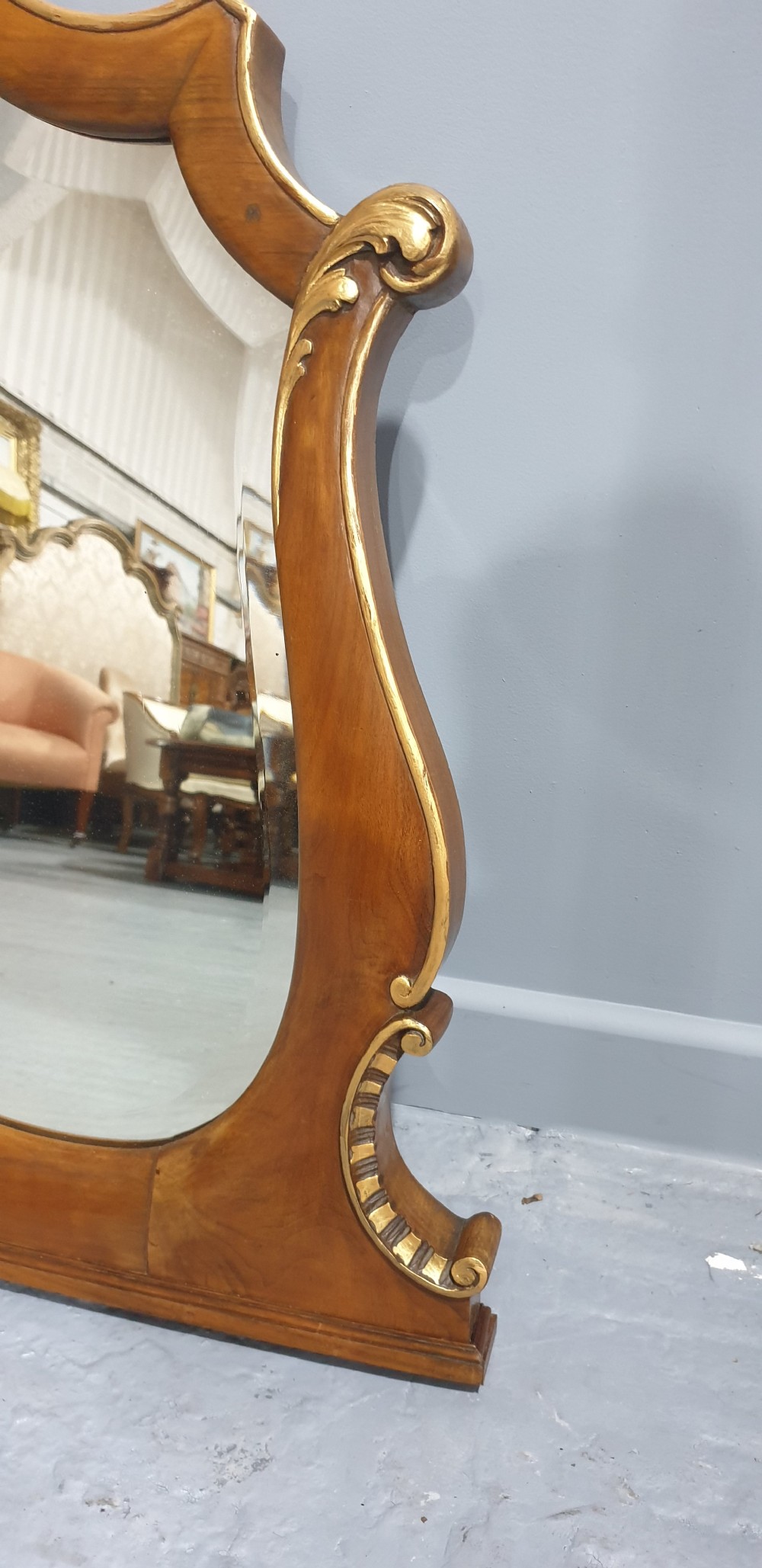 A shaped walnut overmantel mirror featuring gilded beaded borders and leaf accents framing a large central plate. View VI