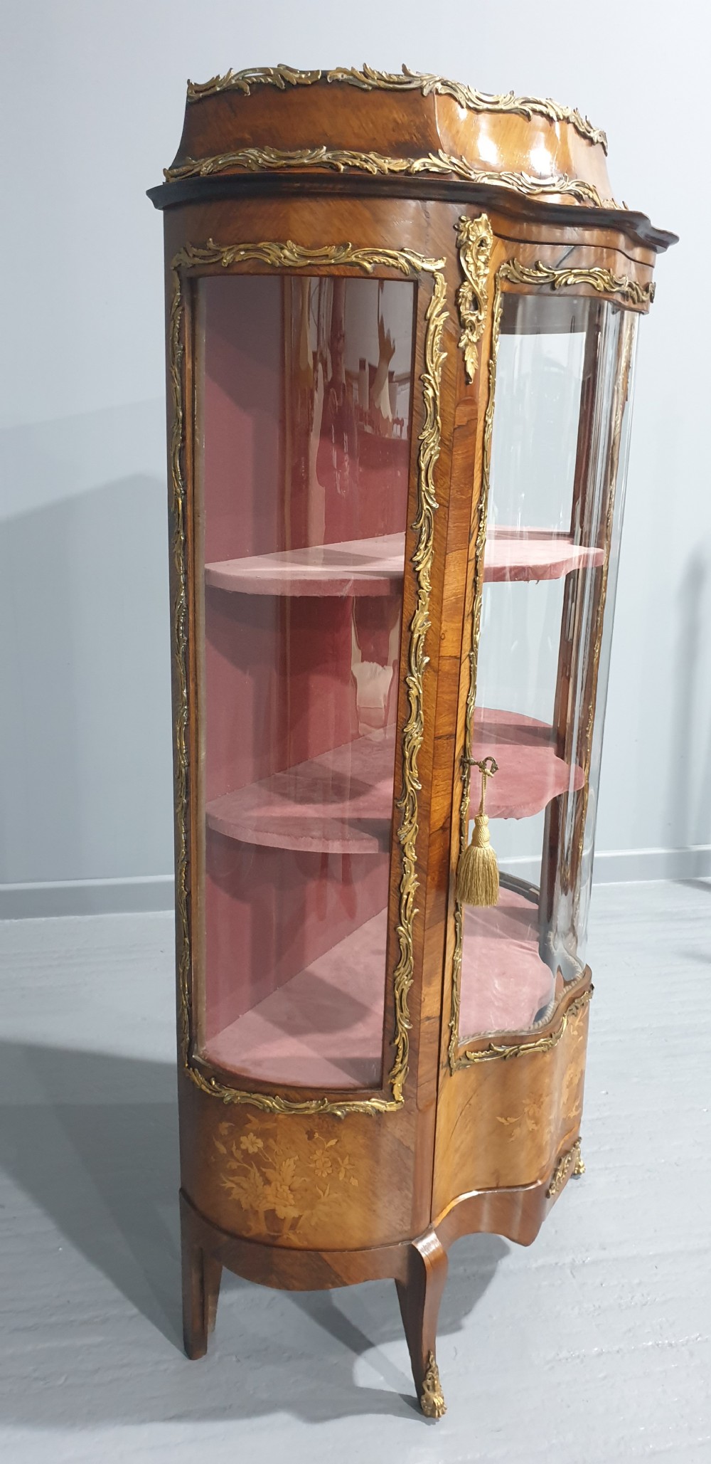An antique French Louis XV style glazed vitrine display cabinet featuring curved glass sides, floral marquetry inlay, and detailed ormolu mounts. View III