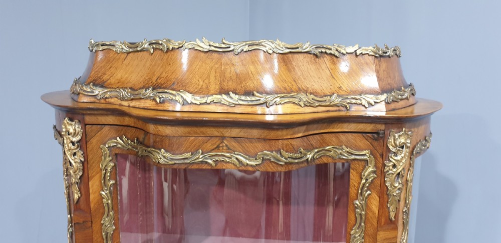 An antique French Louis XV style glazed vitrine display cabinet featuring curved glass sides, floral marquetry inlay, and detailed ormolu mounts. View VIII
