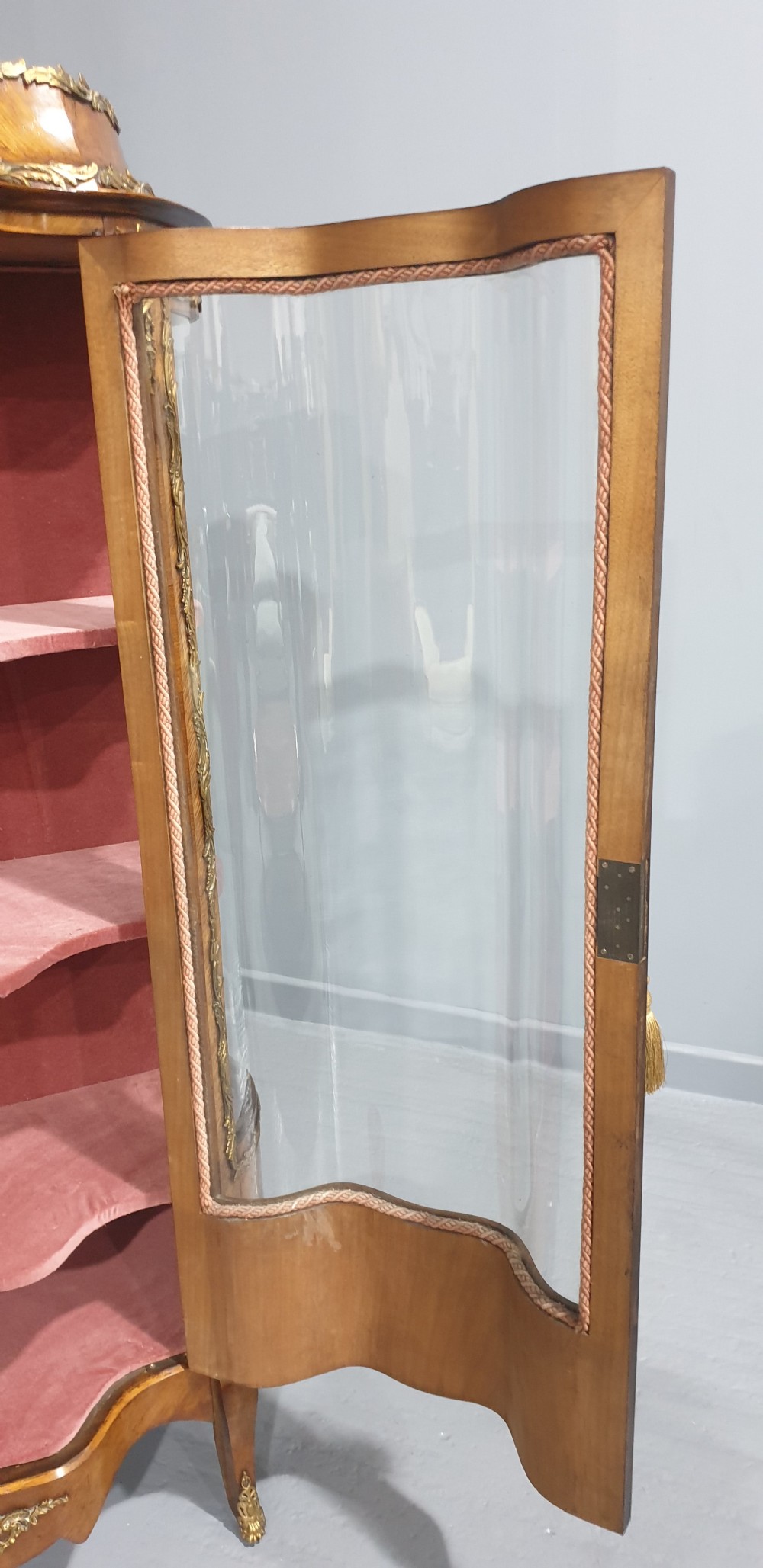 An antique French Louis XV style glazed vitrine display cabinet featuring curved glass sides, floral marquetry inlay, and detailed ormolu mounts. View X