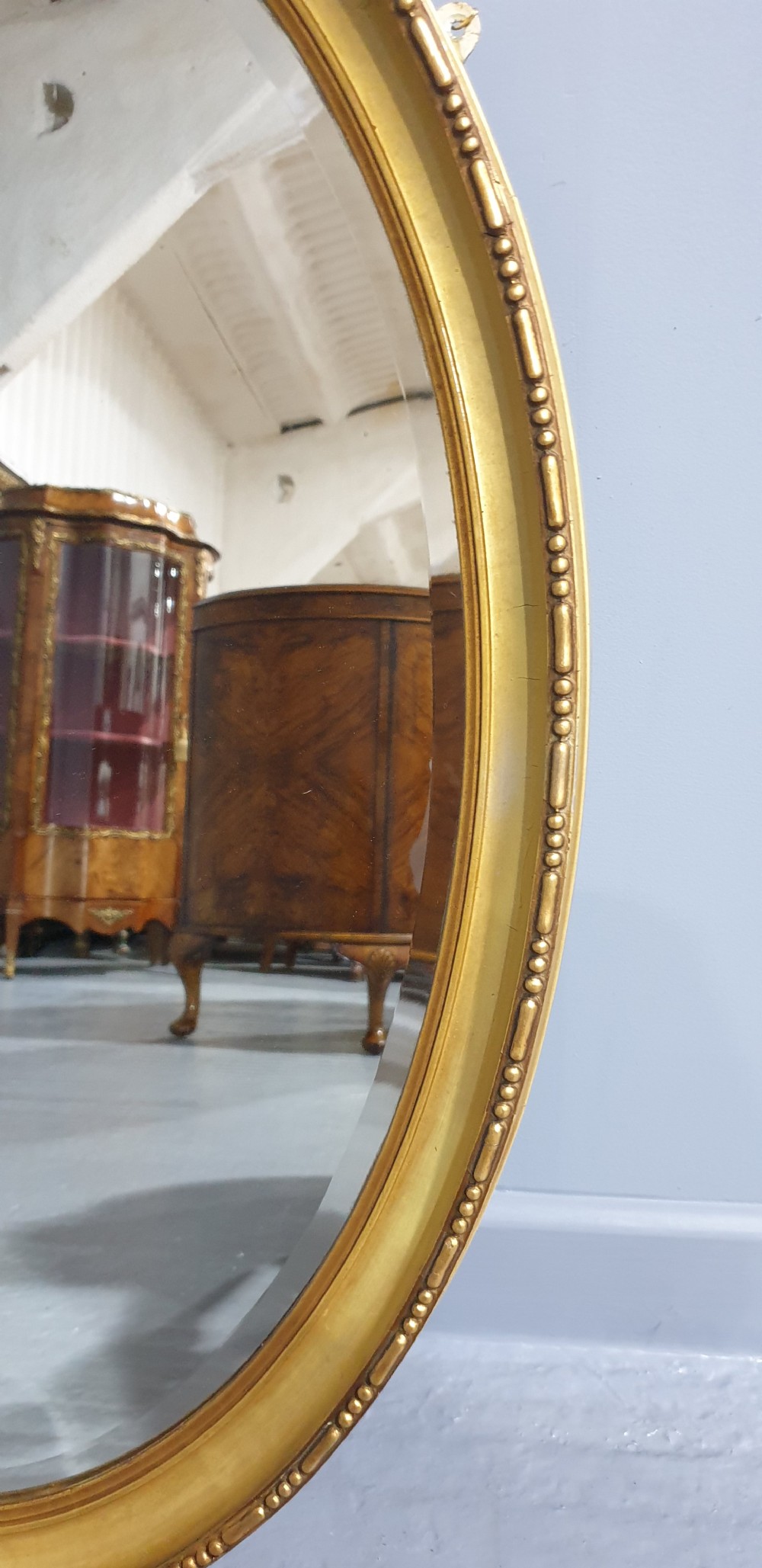 An oval Victorian wall mirror featuring a moulded gold gilt frame with subtle beaded detailing around the inner rim. View III