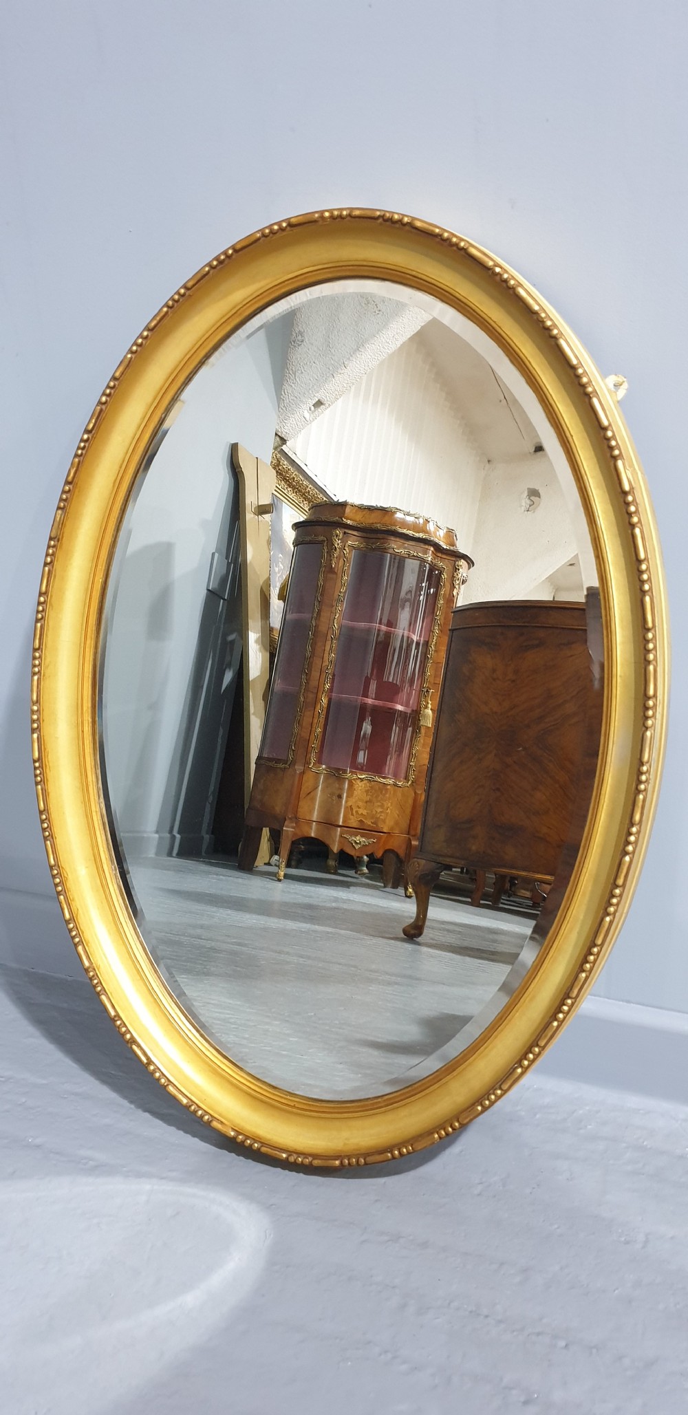 An oval Victorian wall mirror featuring a moulded gold gilt frame with subtle beaded detailing around the inner rim. View IV