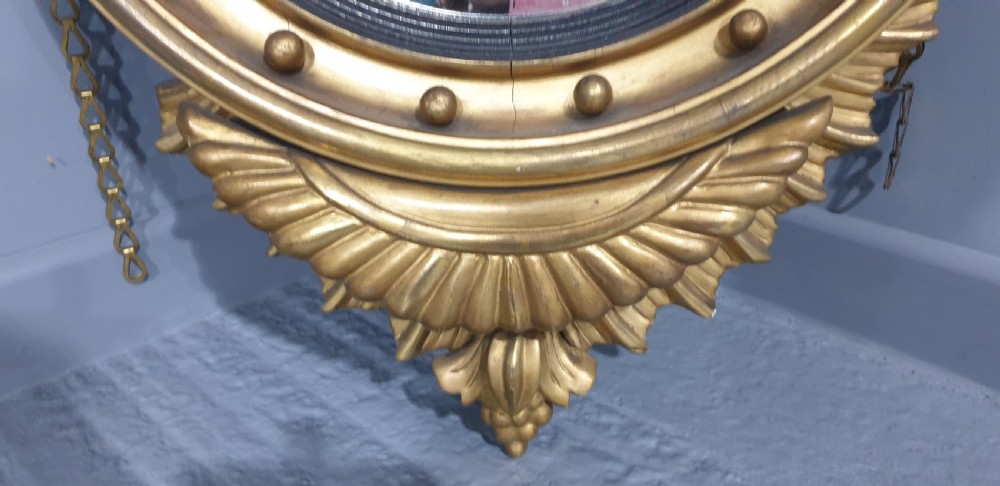 An antique Regency giltwood convex wall mirror featuring a carved eagle cresting, ball-studded circular frame, and acanthus apron. View III