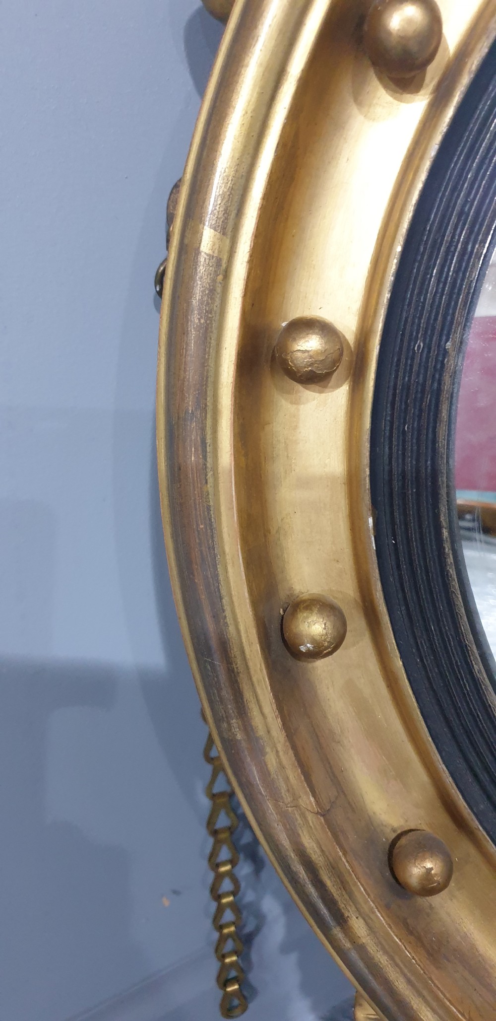 An antique Regency giltwood convex wall mirror featuring a carved eagle cresting, ball-studded circular frame, and acanthus apron. View VI