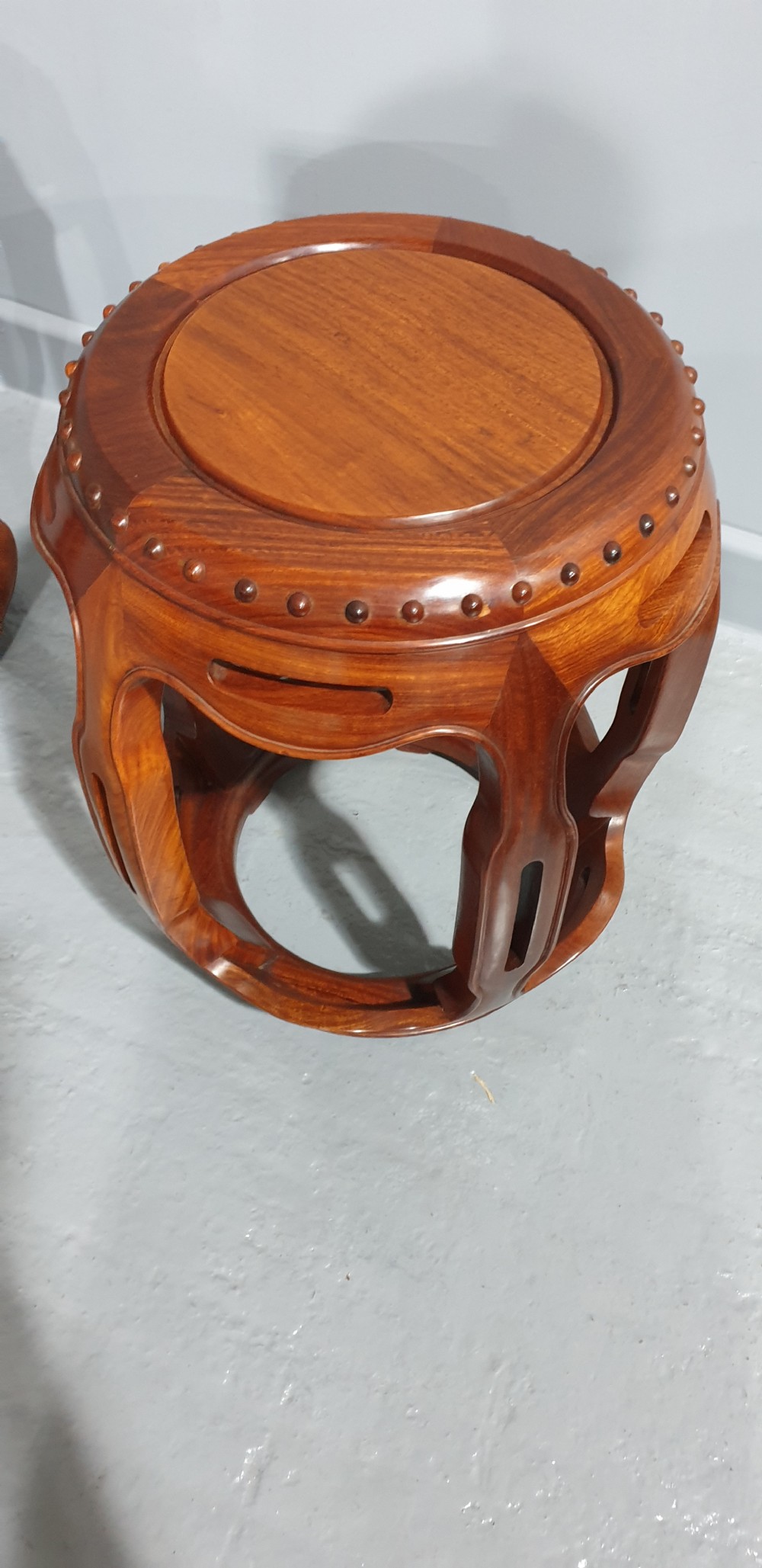 A pair of warm brown carved teak barrel stools featuring openwork sides and carved stud details along the circular top rim. View III