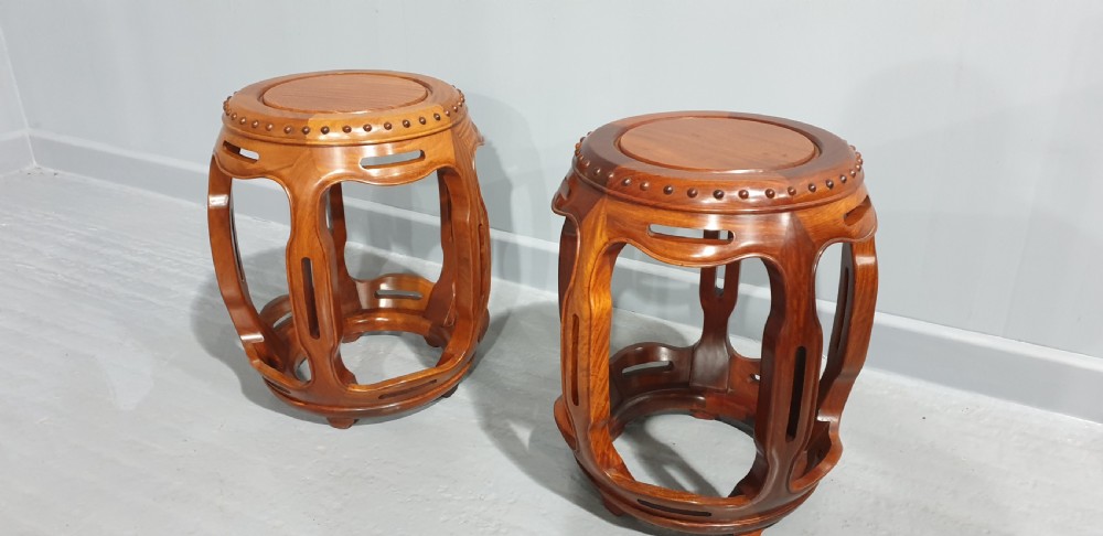 A pair of warm brown carved teak barrel stools featuring openwork sides and carved stud details along the circular top rim. View IV