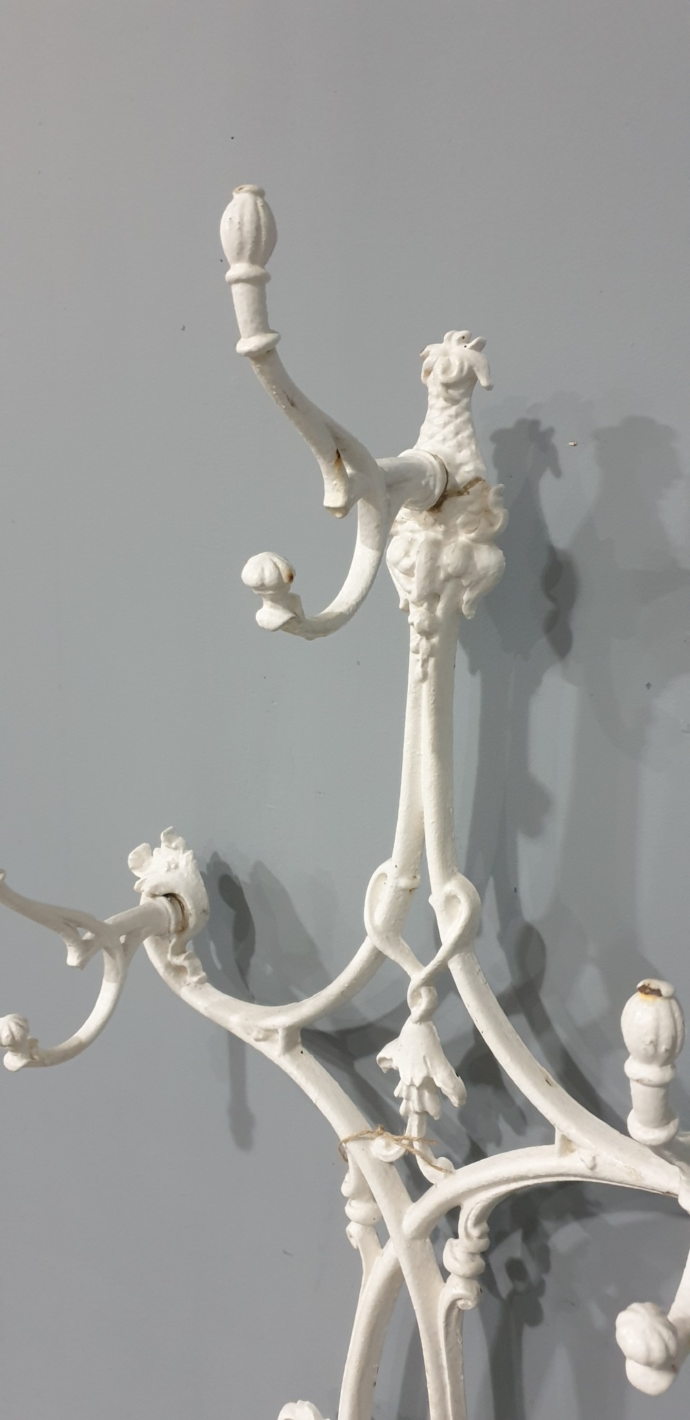 An ornate white painted cast iron hall stand featuring multiple coat hooks, scrollwork frame, umbrella support rings, and an integrated drip tray at the base. View III