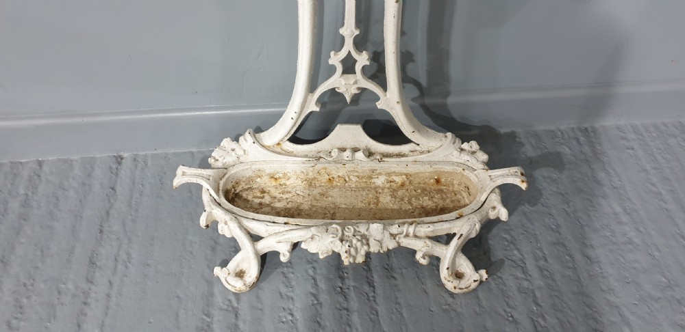 An ornate white painted cast iron hall stand featuring multiple coat hooks, scrollwork frame, umbrella support rings, and an integrated drip tray at the base. View VIII