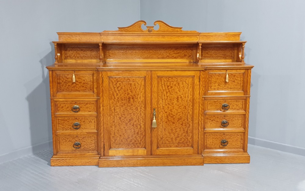 A Victorian satinwood low press cabinet featuring central panelled double doors, flanking drawer stacks, brass drop handles, and an upper scroll gallery. View II