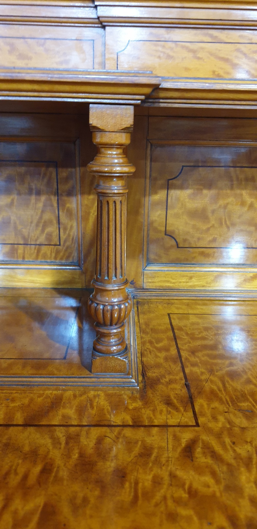 A Victorian satinwood low press cabinet featuring central panelled double doors, flanking drawer stacks, brass drop handles, and an upper scroll gallery. View XI