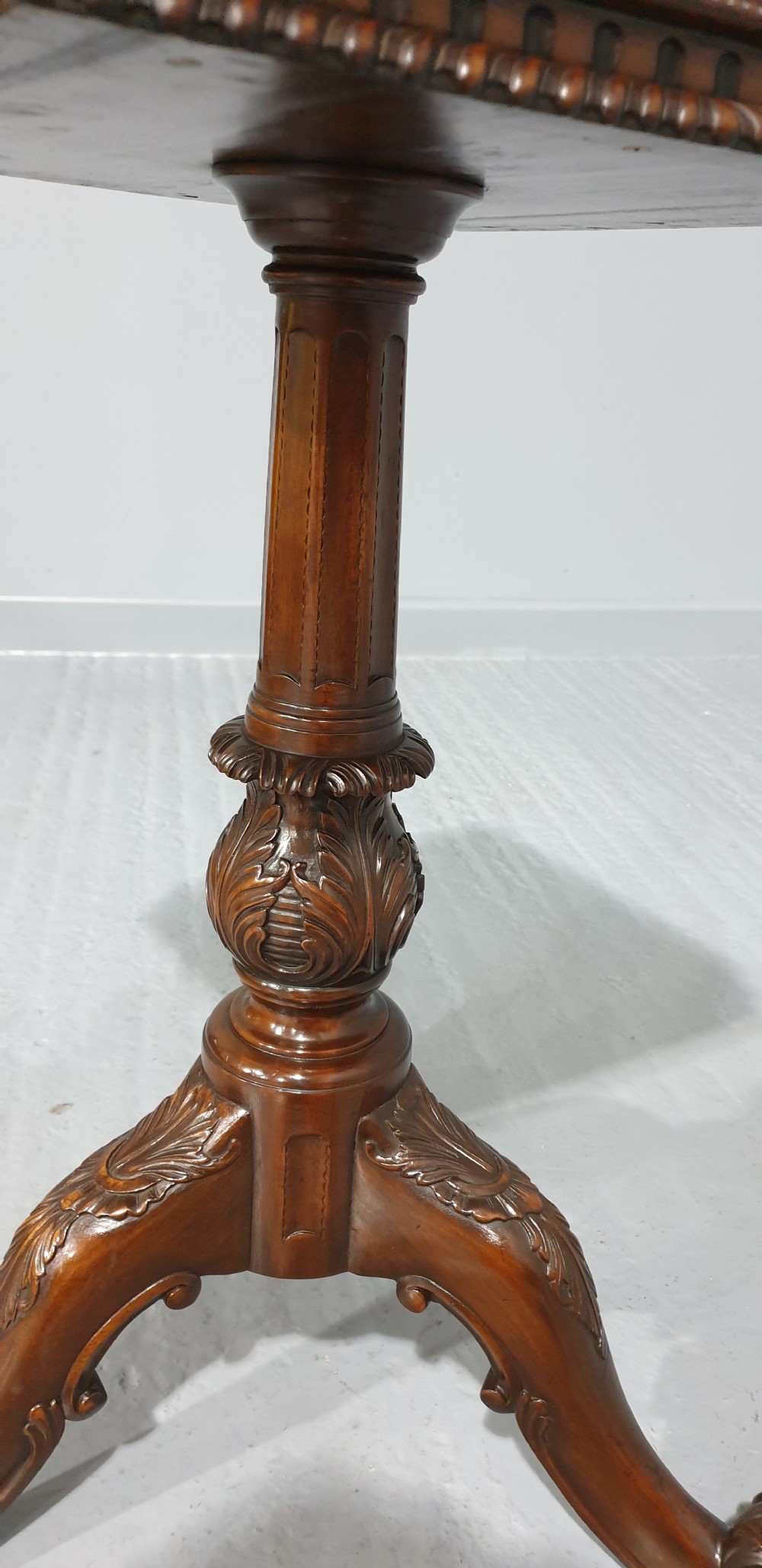 A mahogany tripod occasional table featuring a fretwork gallery top, a pull-out candle slide, a carved central column, and three carved legs. View X