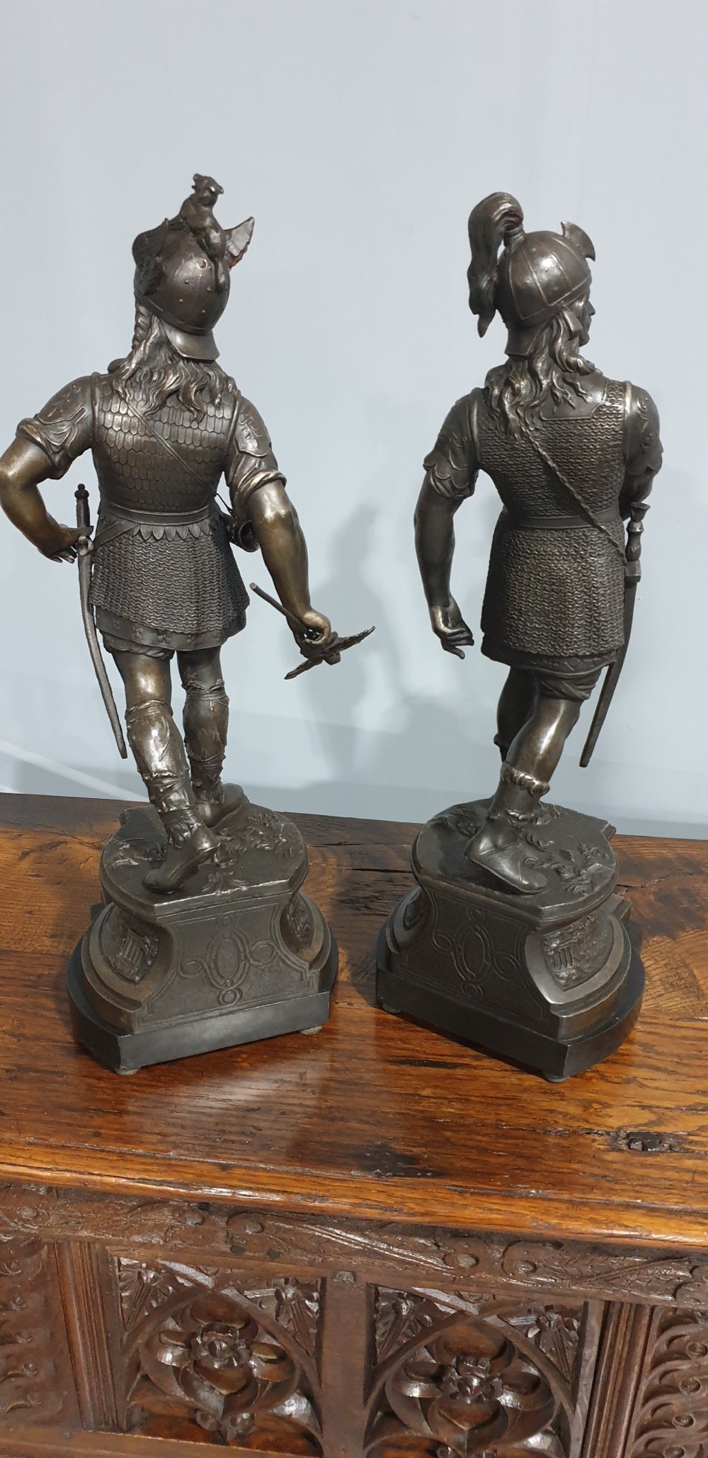 A pair of dark bronze-finished spelter statues depicting classical warriors wearing detailed armour and standing on relief-decorated bases. View IX