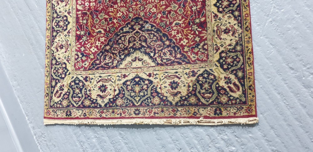 An elongated hand-knotted antique wool runner rug featuring a detailed central medallion and ornate floral motifs in deep red, navy blue, and cream colours. View V