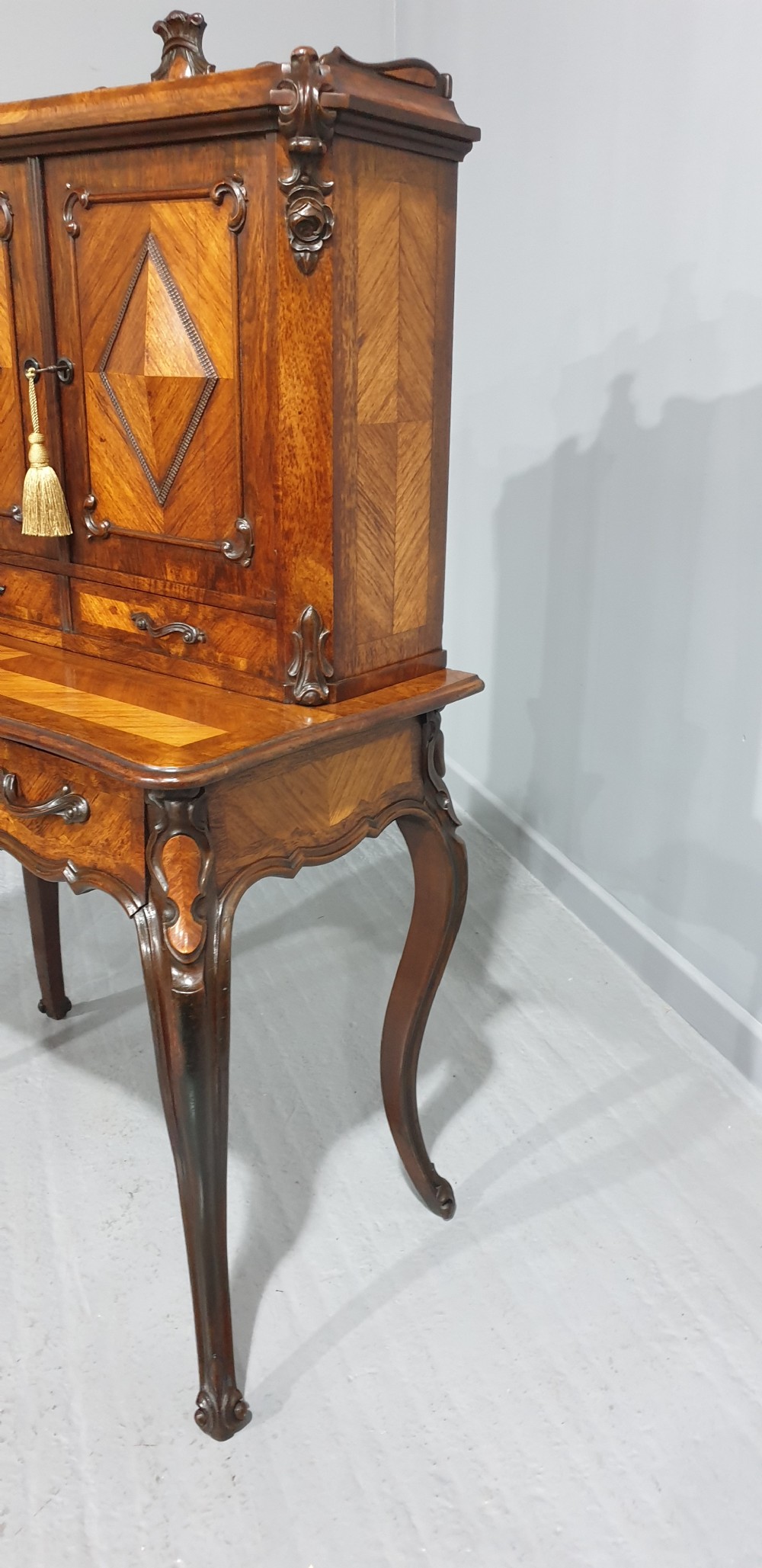 A French Bonheur du Jour writing desk in warm brown walnut with geometric diamond marquetry, cabriole legs, and an upper cabinet section with twin doors. View VI