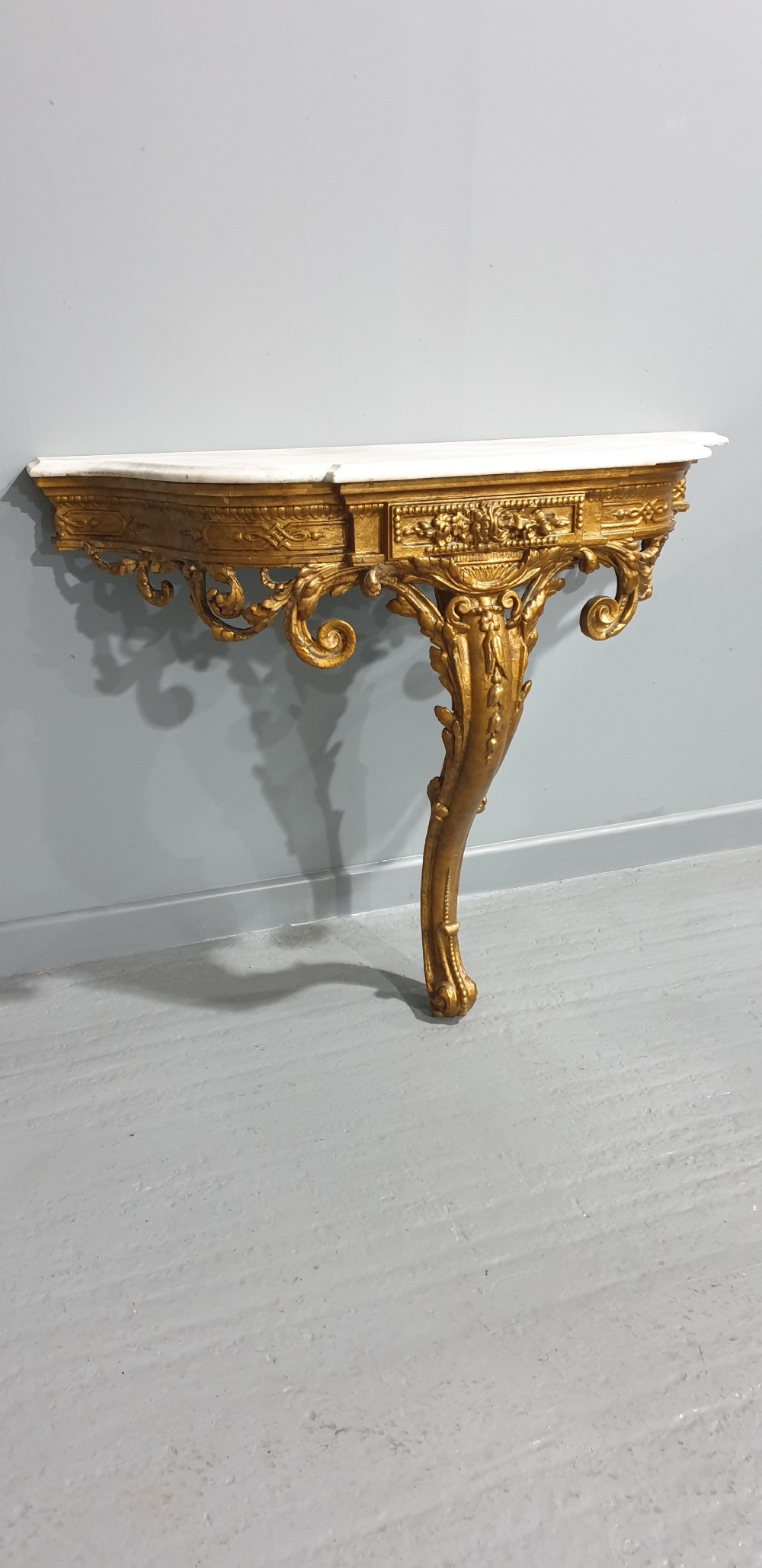 A 19th-century French giltwood wall-mounted console table featuring a single carved leg and a white marble top. View II