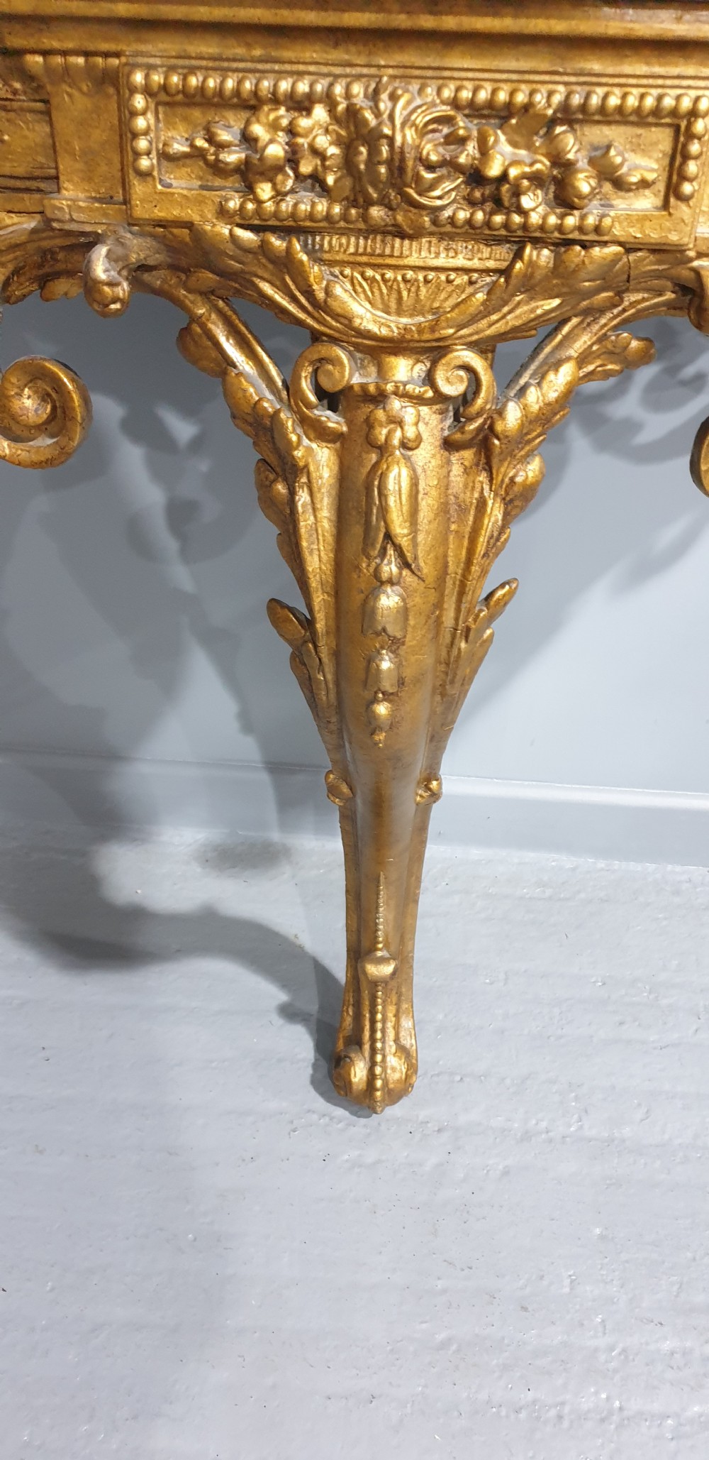 A 19th-century French giltwood wall-mounted console table featuring a single carved leg and a white marble top. View VII