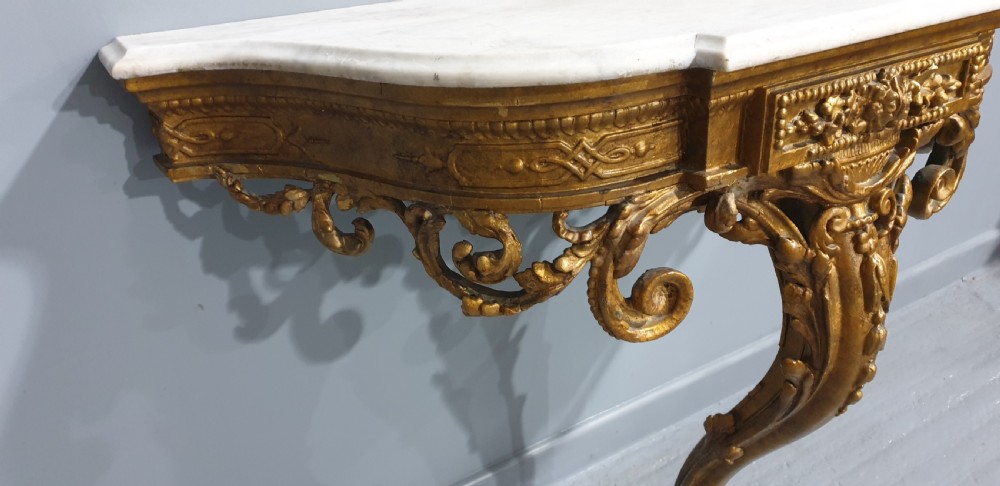 A 19th-century French giltwood wall-mounted console table featuring a single carved leg and a white marble top. View IX