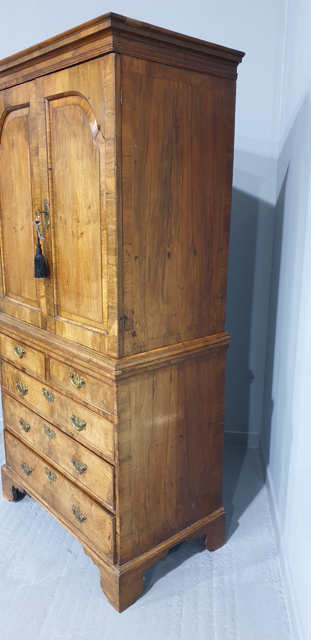 A George I walnut secretaire chest of small proportions featuring an upper double cabinet with arched door panels over a base of four drawers with brass hardware. View VI