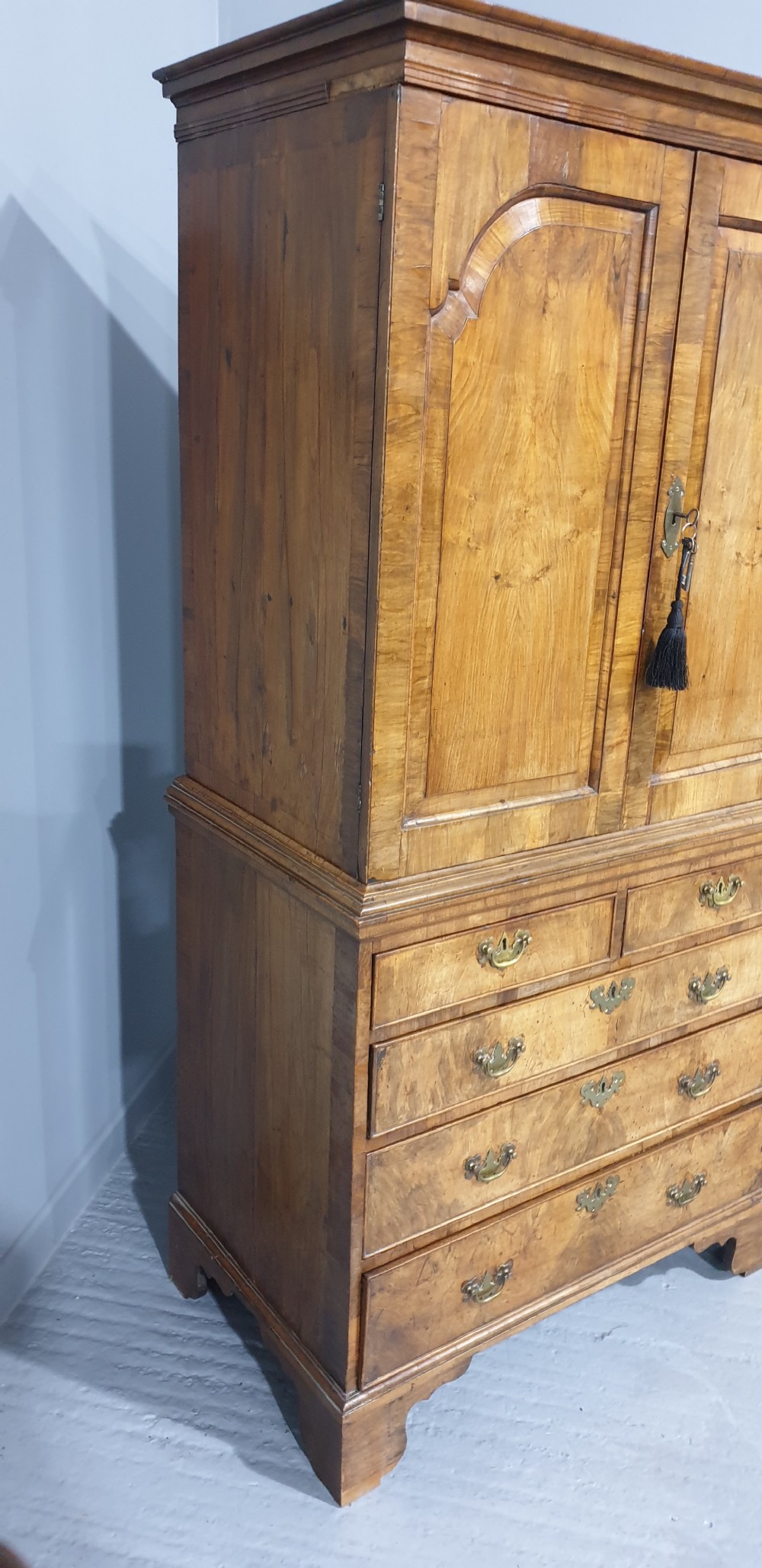A George I walnut secretaire chest of small proportions featuring an upper double cabinet with arched door panels over a base of four drawers with brass hardware. View VII